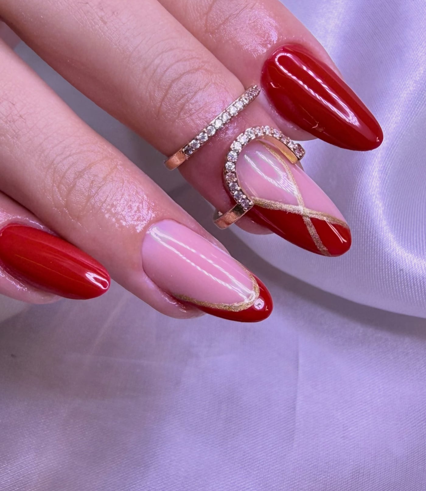 Mão com unhas vermelhas em formato amendoado e francesinha com fio dourado