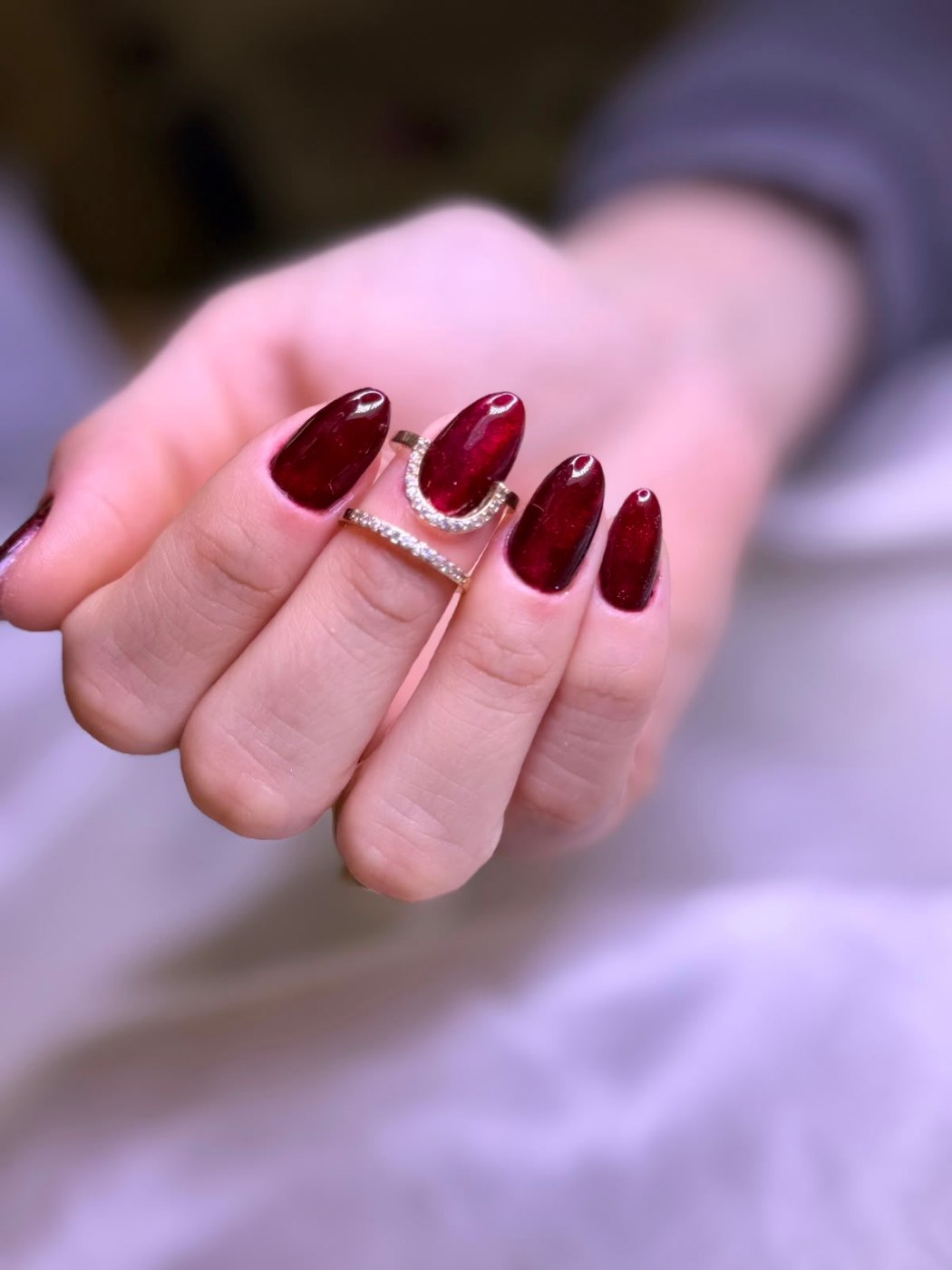 Unhas vinho escuro em formato amendoado, com efeito cat eye